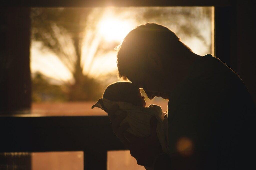 man carrying baby drawing their foreheads